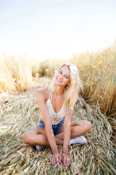 Attraktive Blondine, die im Sommer auf einem Roggenfeld spaziert und posiert — Stockfoto
