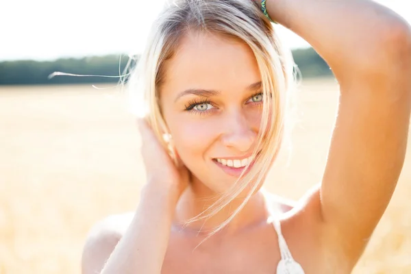 Attractive blonde walking and posing on a rye field in summer da — Stock Photo, Image