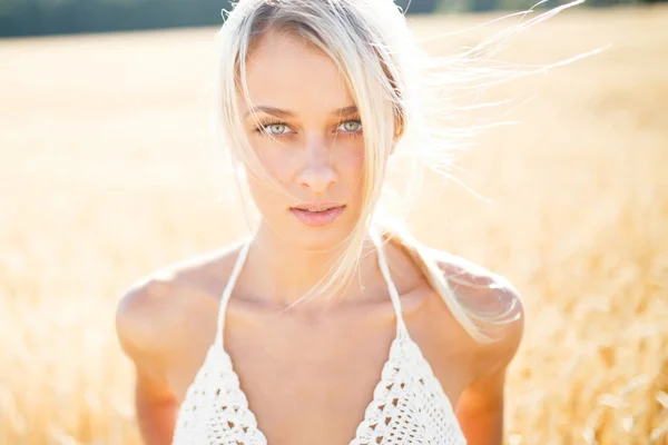 Attractive blonde walking and posing on a rye field in summer da