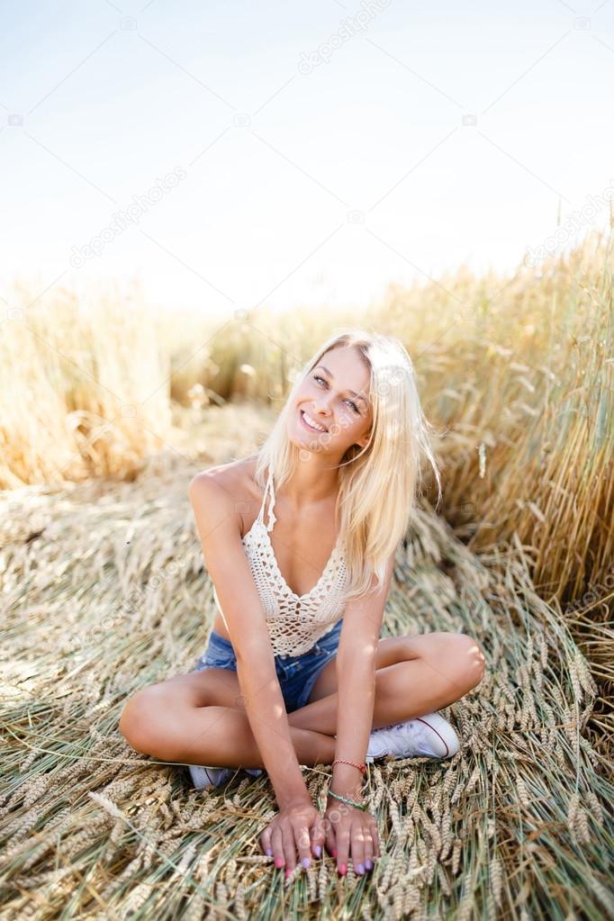 Attractive blonde walking and posing on a rye field in summer da