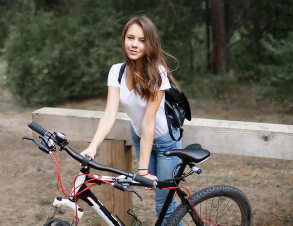 A menina no passeio de bicicleta na floresta em uma bicicleta de montanha . — Fotografia de Stock