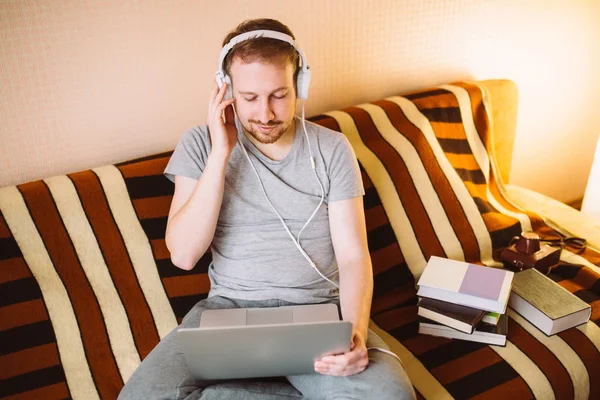 Un giovane uomo che ascolta la musica su un computer portatile — Foto Stock