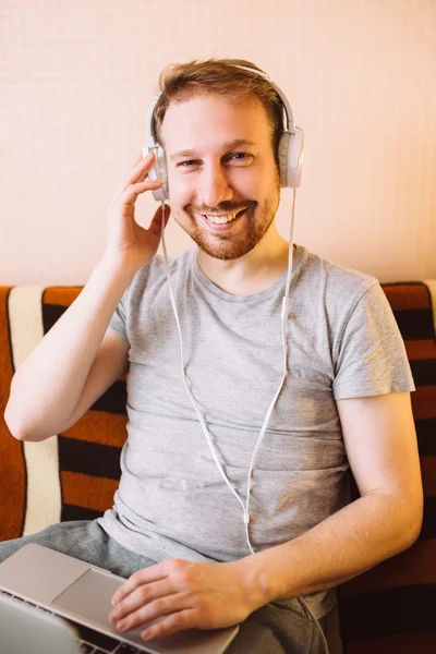 Un giovane uomo che ascolta la musica su un computer portatile — Foto Stock