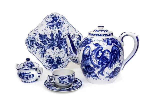 Teiera di porcellana, tazza, piattino, zuccheriera e piatto in stile popolare dipinto di blu su sfondo bianco — Foto Stock