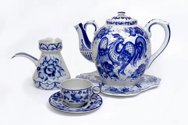 Фарфоровый чайник, чашка, блюдце и сливки в народном стиле окрашены синий на белом фоне Лицензионные Стоковые Фото