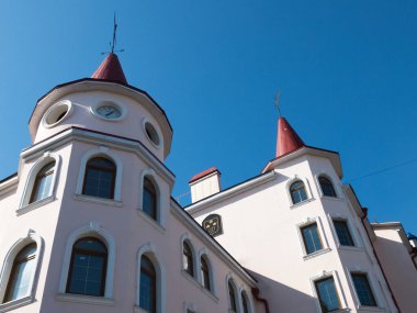 Kulesi ve saati olan bir ev. Üzerinde kule ve ek bina olan yarı antika bir ev. Bir de saat var. Gökyüzünün arka planında kırmızı çatılı güzel bir ışık evi..