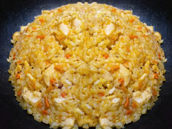 A large vat of cooked pilaf or rice with meat, carrots, onions and spices. Street food at the party. Eastern dish. Large cauldron with freshly cooked rice. Traditional cuisine