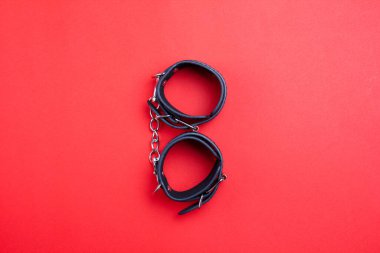 Kırmızılı BDSM siyahına itaat için deri kelepçeler. Metal bir zincirle bağlanmış. Ceza ve rol oynamak için prangalar