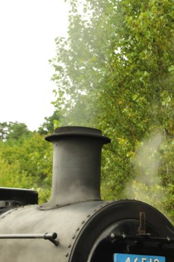 Kömür dolu buharlı lokomotif, yol boyunca ilerliyor.