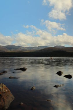 Güneş altında Morlich Gölü 'nün etrafında oynuyorlar.