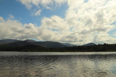 Güneş altında Morlich Gölü 'nün etrafında oynuyorlar.