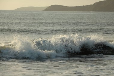 Atlantik dalgaları Carlyon körfezine doğru süpürüyor kumsaldaki kumu temizliyor ve İngiltere 'nin güney kıyısı ve Cornwall ilçesi açıklarındaki fırtınayı takiben kayaların üzerine çarpıyor.