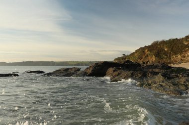 Atlantik dalgaları Carlyon körfezine doğru süpürüyor kumsaldaki kumu temizliyor ve İngiltere 'nin güney kıyısı ve Cornwall ilçesi açıklarındaki fırtınayı takiben kayaların üzerine çarpıyor.