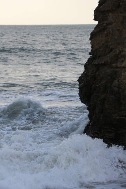 Atlantik fırtınası dalgaları İngiltere 'nin güney batı kıyısındaki Cornwall' daki Carlyon körfezi plajında kayaların ve kumların üzerine düşüyor.