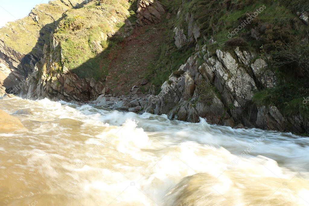 The Heddon river swollen by heavy rainfall and floodwater crashing through Heddon valley on the way out to sea on the coast of North Devon in the south west of England