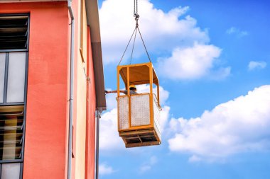 İnşaatta çalışan bir işçi, mavi gökyüzünün arkasındaki evin duvarını onarıyor..