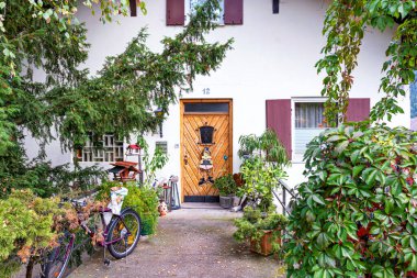 Tırmanış bitkileri, bisikletler, ağaçlar ve çalılarla dekore edilmiş bir evin girişi: FUSSEN, GERMANY - 18 Eylül 2018