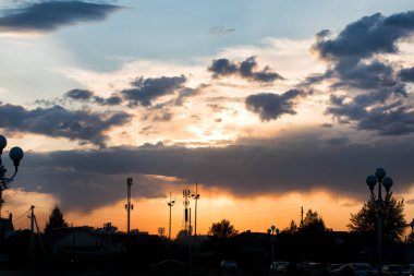  Bulutlu gökyüzünün arkasında parlak bir günbatımı.