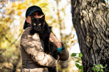 Siyah bir rakun yavrusu ve sonbahar ormanında bir kadın..