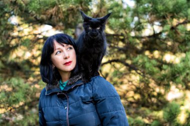 Kara maine rakunu kedi ve sonbahar ormanında bir kız..