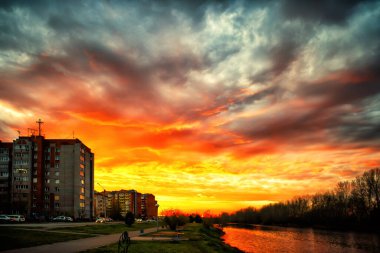 Bulutlu gökyüzünün arkasında parlak bir günbatımı.