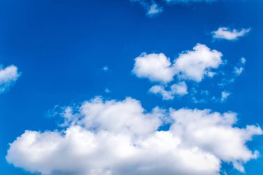 Mavi gökyüzünün arka planında kabarık beyaz bulutlar.