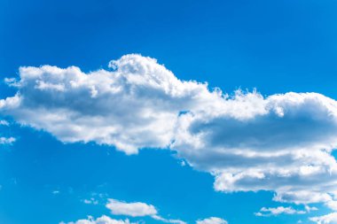 Mavi gökyüzünün arka planında kabarık beyaz bulutlar.