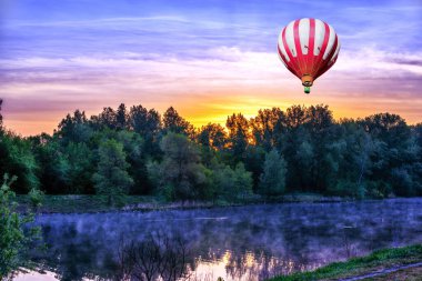 Nehrin üzerinde güzel bir gün doğumu ve sabahın erken saatlerinde gökyüzünde sıcak hava balonu..