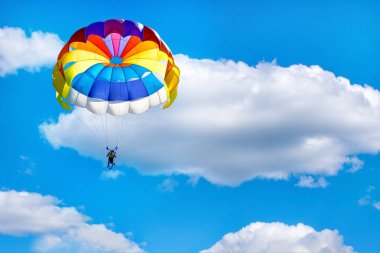 Mavi bulutlu gökyüzünün arka planında paraşüt kullanarak paraşüt kullanmak.