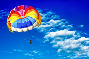 Mavi bulutlu gökyüzünün arka planında paraşüt kullanarak paraşüt kullanmak.