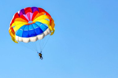 Mavi gökyüzünün arka planında paraşüt kullanarak para yelkeni.