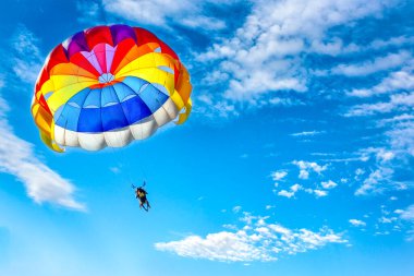 Mavi bulutlu gökyüzünün arka planında paraşüt kullanarak paraşüt kullanmak.