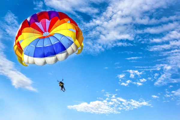 Mavi bulutlu gökyüzünün arka planında paraşüt kullanarak paraşüt kullanmak.