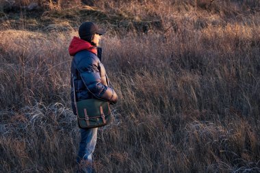 Gün batımında tarlada omuz çantası olan ceketli genç bir kadın.. 