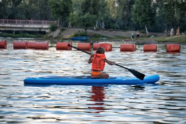 Güneşli bir günde bir nehirde sörf yapan bir kız..