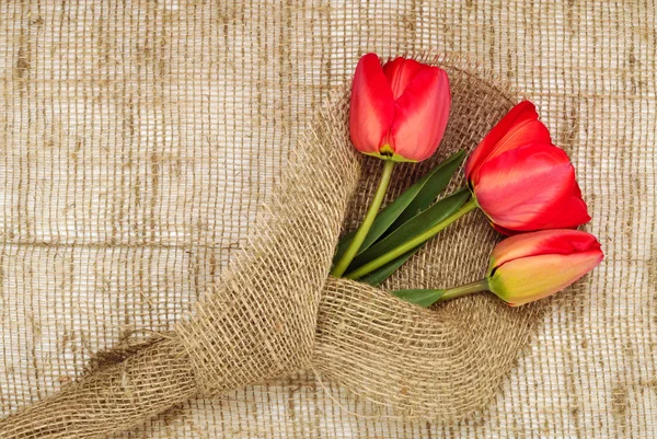 Bouquet of red tulips on burlap background — Stock Photo, Image