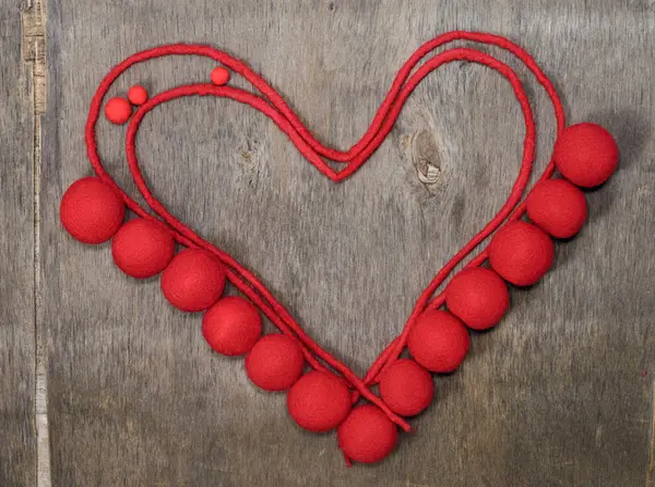 Circuit de coeur rouge et perles en mérinos de laine sur le fond en bois. Silhouette coeur — Photo