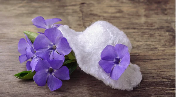 White hat and a bunch of small lilac flowers on the wooden background — Stock Photo, Image