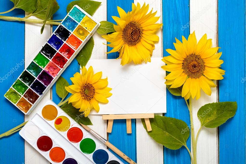 sunflowers, painting and easel on the background of colored wooden boards