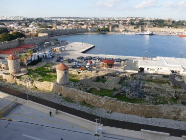 Arka planda Rodos, Rodos, Yunanistan 'daki Embaria limanındaki değirmenlerin ve eski şehir surlarının manzarası var.