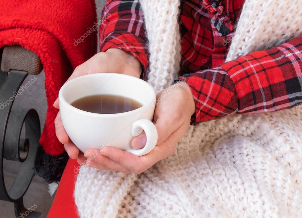 Woman's hands holding cups of tea or coffee dressed in red and white festive clothes.