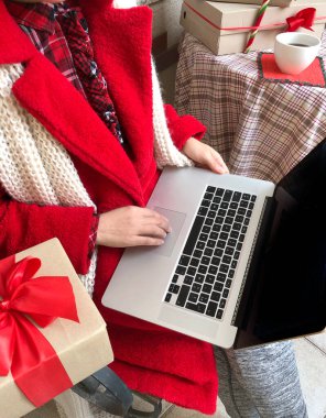 Noel ve yeni yıl arifesinde dizüstü bilgisayar kullanan kırmızı kürklü bir kadın..