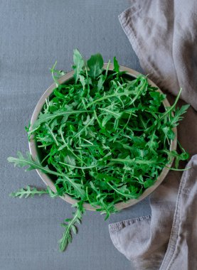Gri arka planda taze yeşil roka tabakası.