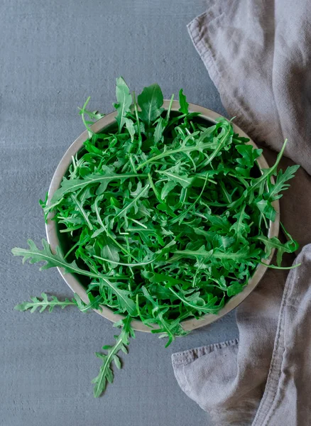 Gri arka planda taze yeşil roka tabakası.