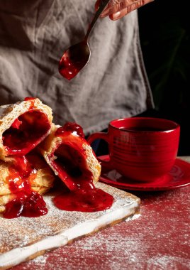 Dişi Eller, masada erik ya da frenk üzümü reçeli ile bir puf pişirir..
