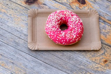 Tahta arka plandaki kağıt teslimat tabağında Pembe Kek, üst manzara..