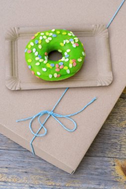 Kağıt teslimat kutusunda yeşil pasta, ahşap arka planda mavi fiyonk, üst manzara..