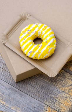 Tahta arka plandaki kağıt teslimat tabağında sarı pasta, üst manzara..