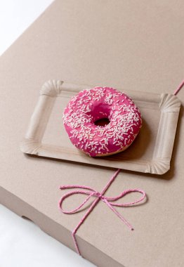 Kağıt teslimat kutusunda pembe kek, beyaz arka planda kırmızı fiyonk, üst görünümde..