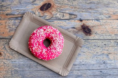 Tahta arka plandaki kağıt teslimat tabağında Pembe Kek, üst manzara..